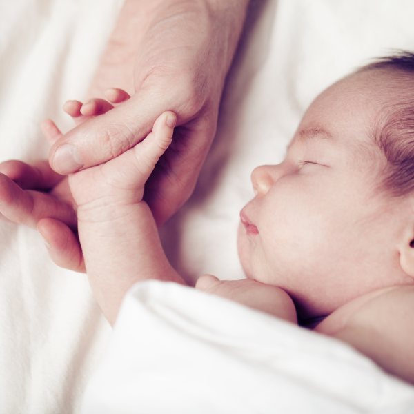 Newborn baby and his father's hand - care and safety concept